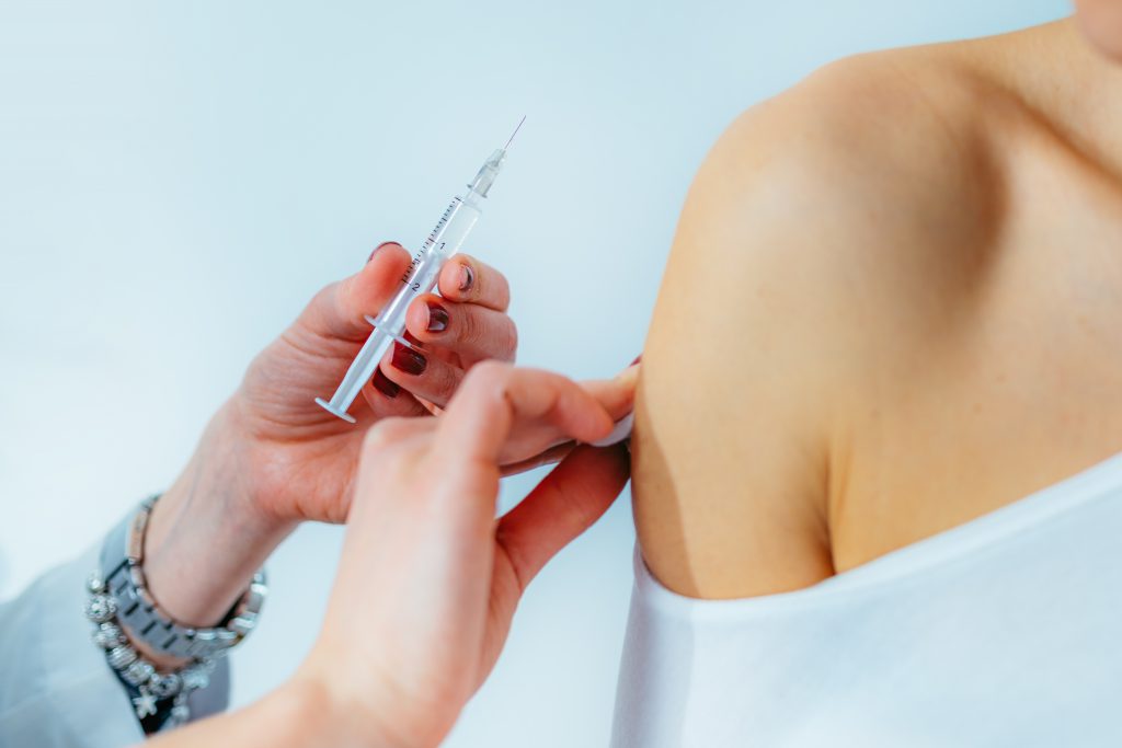 Doctor cleaning an adult's shoulder before giving them an immunization.