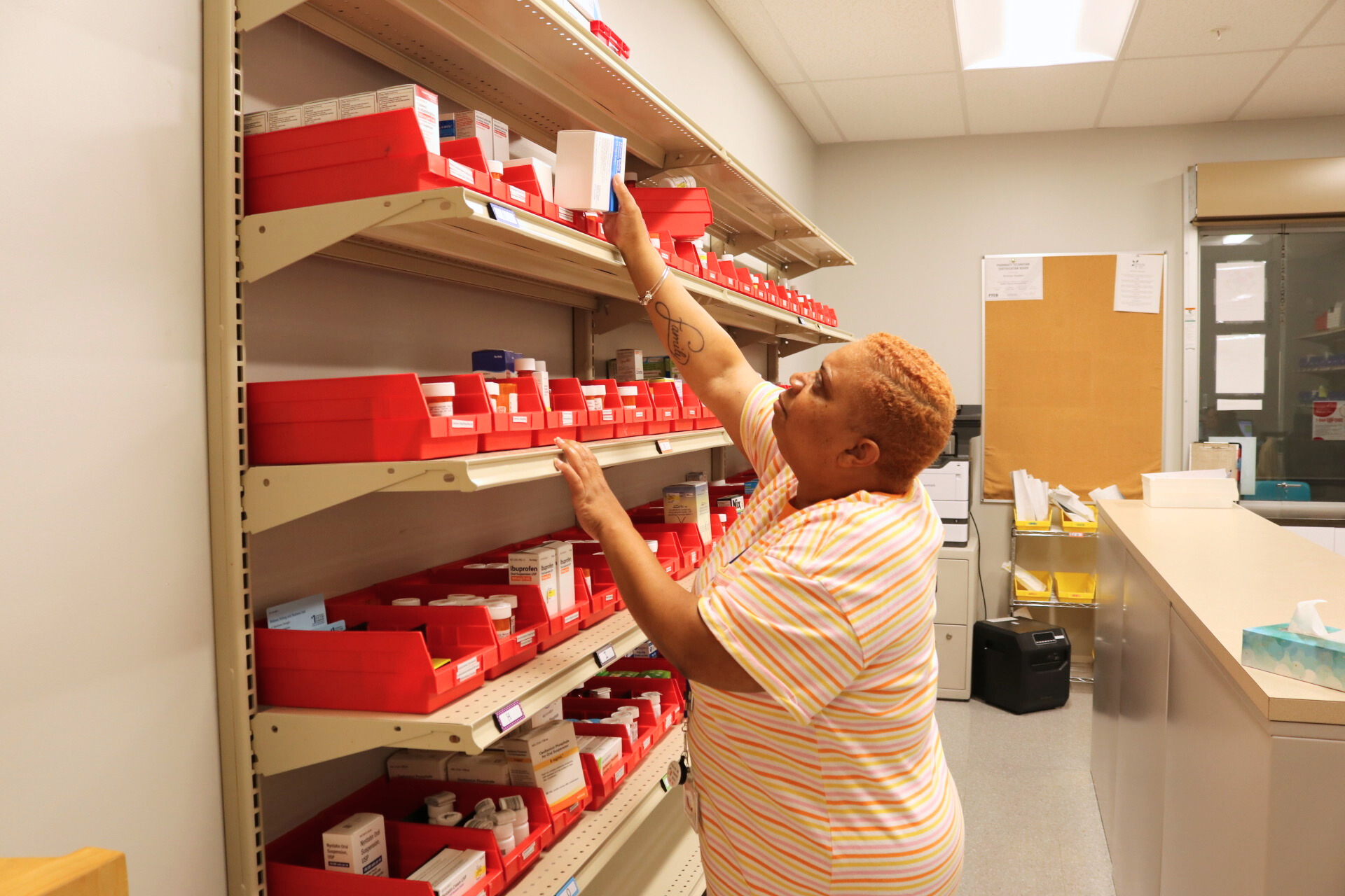 Dispensary provider searching for a medication on the shelves.