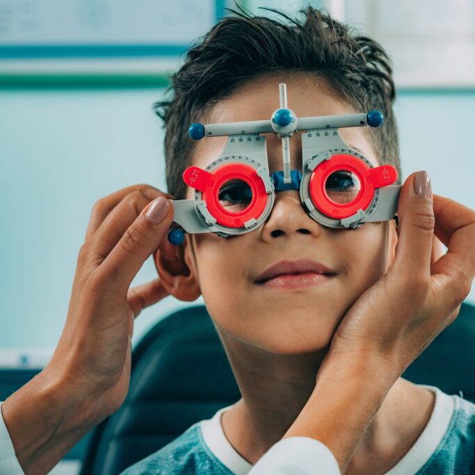 Eye doctor performing an eye exam on a young patient.